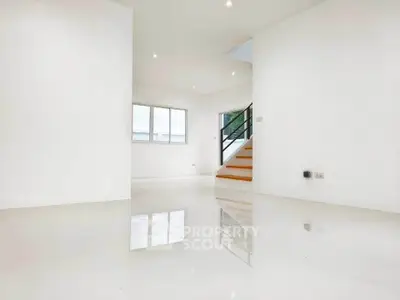 Spacious modern living room with glossy floors and staircase, ideal for contemporary living.
