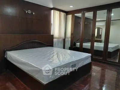 Spacious bedroom with elegant wooden furnishings and large mirrored wardrobe.