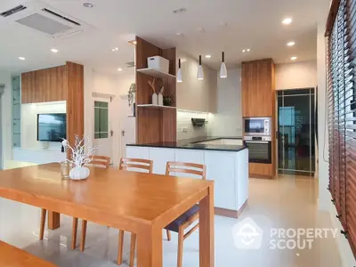 Modern open kitchen and dining area with wooden accents and sleek appliances