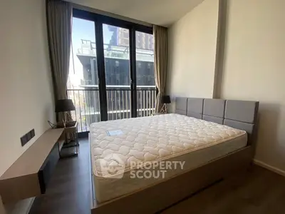 Modern bedroom with large window and stylish decor in urban apartment.