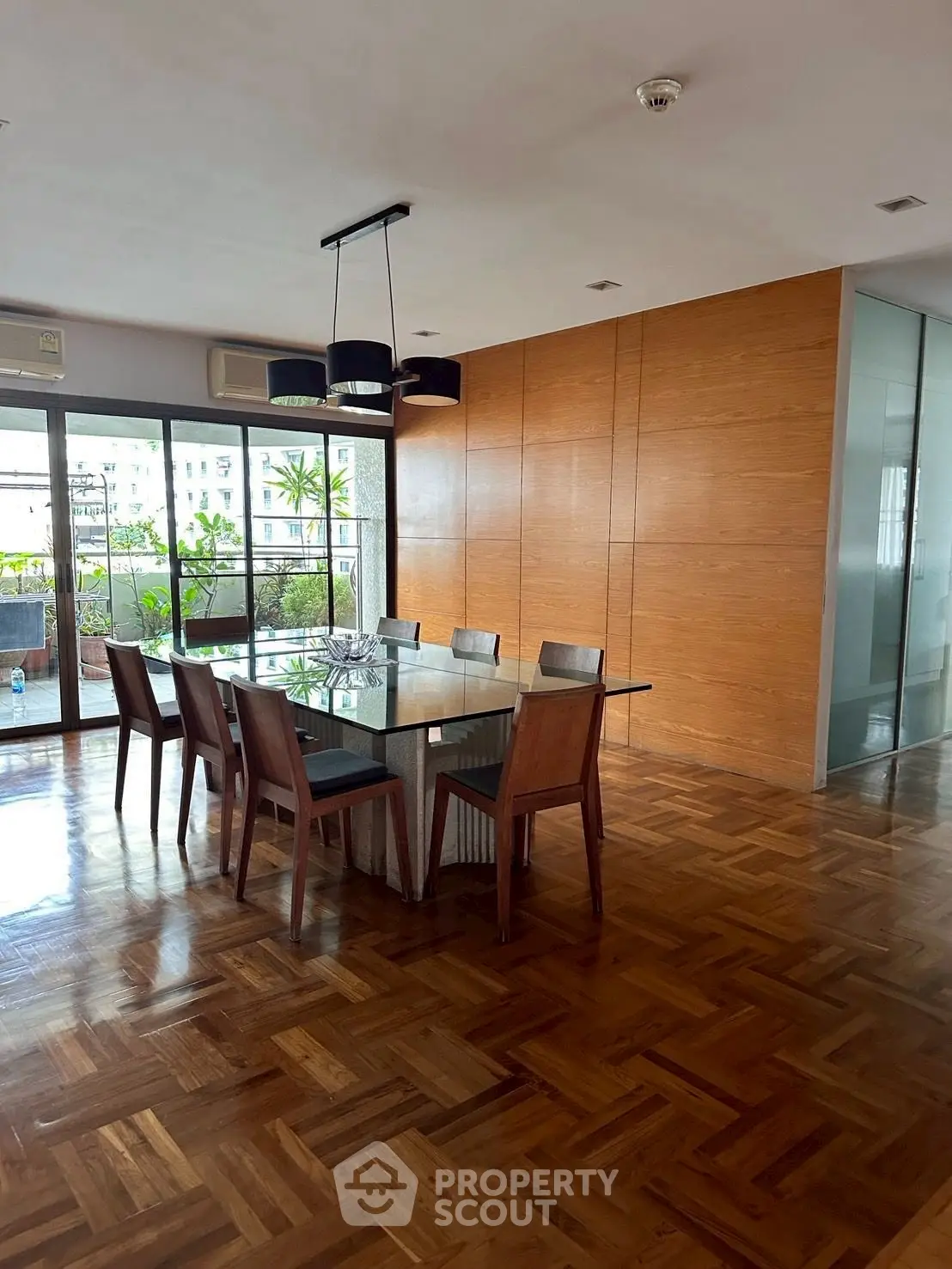 Spacious dining area with elegant wooden flooring and large windows opening to a balcony.