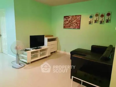 Cozy living room with modern black sofa and TV setup, perfect for relaxation.