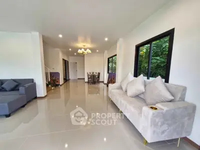 Spacious modern living room with elegant decor and large windows overlooking lush greenery.