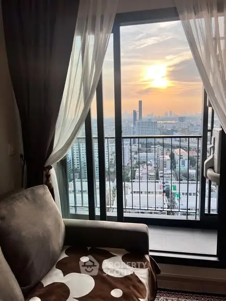 Stunning city view from a cozy living room with balcony at sunset.