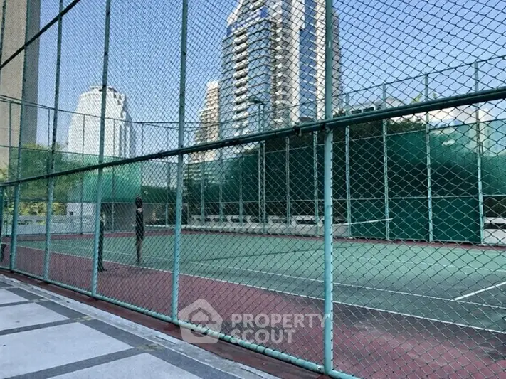 Spacious urban tennis court with skyscraper backdrop, ideal for sports enthusiasts seeking city living.