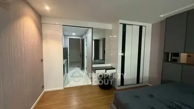 Modern bedroom with sleek design and wooden flooring, featuring a mirrored wardrobe and cozy lighting.