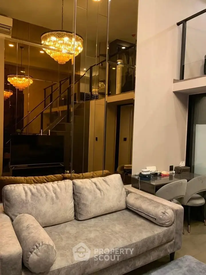 Luxurious modern living room with elegant chandelier and stylish gray sofa in a duplex apartment.