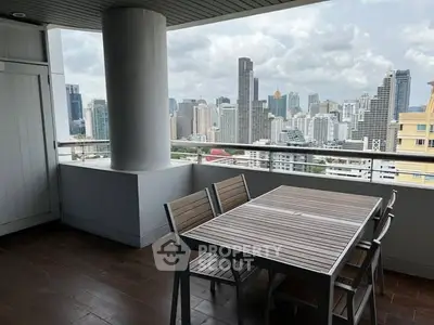 Stunning city view from a spacious balcony with modern outdoor dining set.