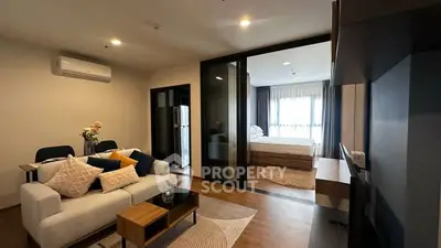 Modern open-plan living room with cozy seating and stylish decor adjacent to a bedroom.