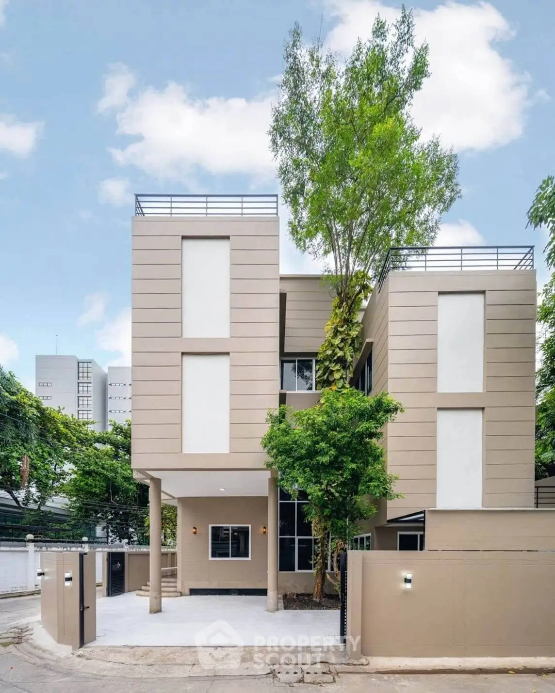 Modern three-story house with sleek design and lush greenery in urban setting.
