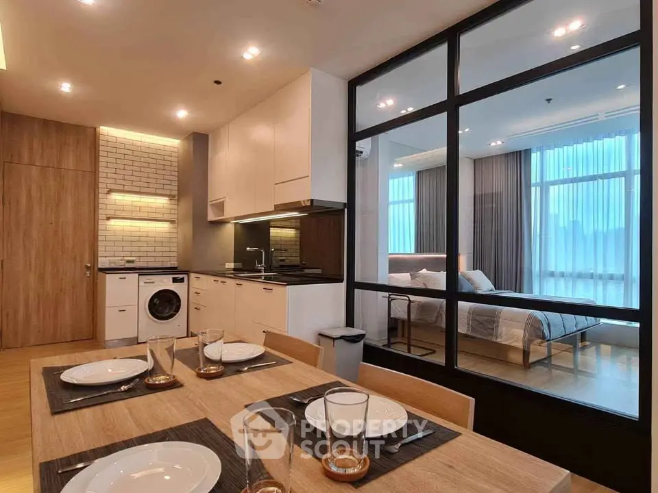 Modern open-layout kitchen and dining area with view into stylish bedroom