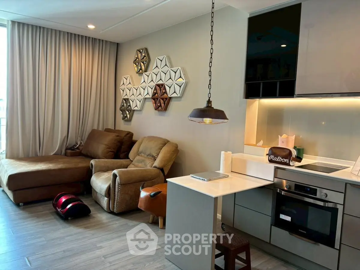 Modern living room with cozy seating and stylish kitchen in open layout apartment.