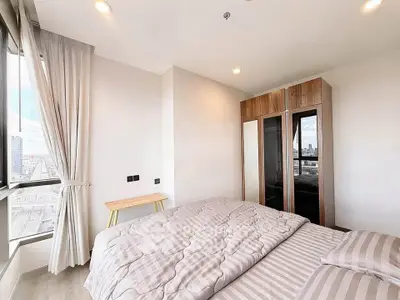 Bright and airy bedroom with city view, featuring modern wardrobe and cozy bedding.