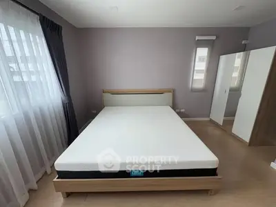 Spacious bedroom with modern decor and large windows for natural light.