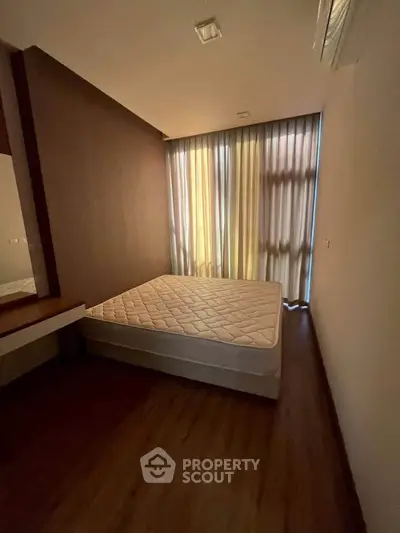 Cozy bedroom with natural light and minimalist design, featuring a comfortable mattress and elegant wooden flooring.