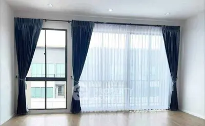 Spacious living room with large windows and elegant curtains, offering ample natural light and modern design.