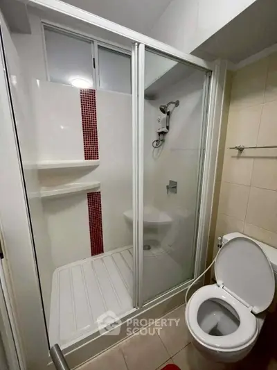 Modern bathroom with glass shower enclosure and toilet in a compact layout.