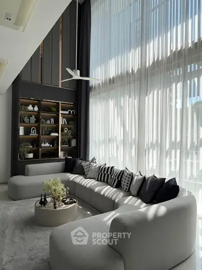 Luxurious living room with high ceilings, elegant decor, and abundant natural light.