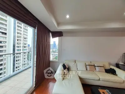 Spacious living room with modern sofa and city view balcony in high-rise apartment.
