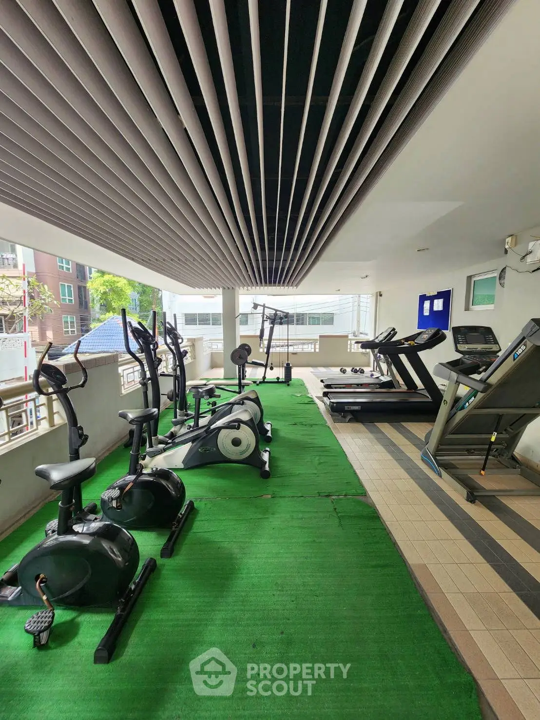 Modern gym with exercise equipment in a residential building, featuring treadmills and stationary bikes.