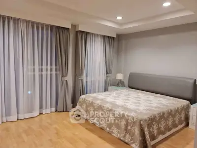 Spacious bedroom with elegant curtains and cozy bed in modern apartment.