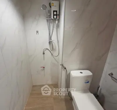 Modern bathroom with sleek shower and toilet, featuring elegant marble tiles.