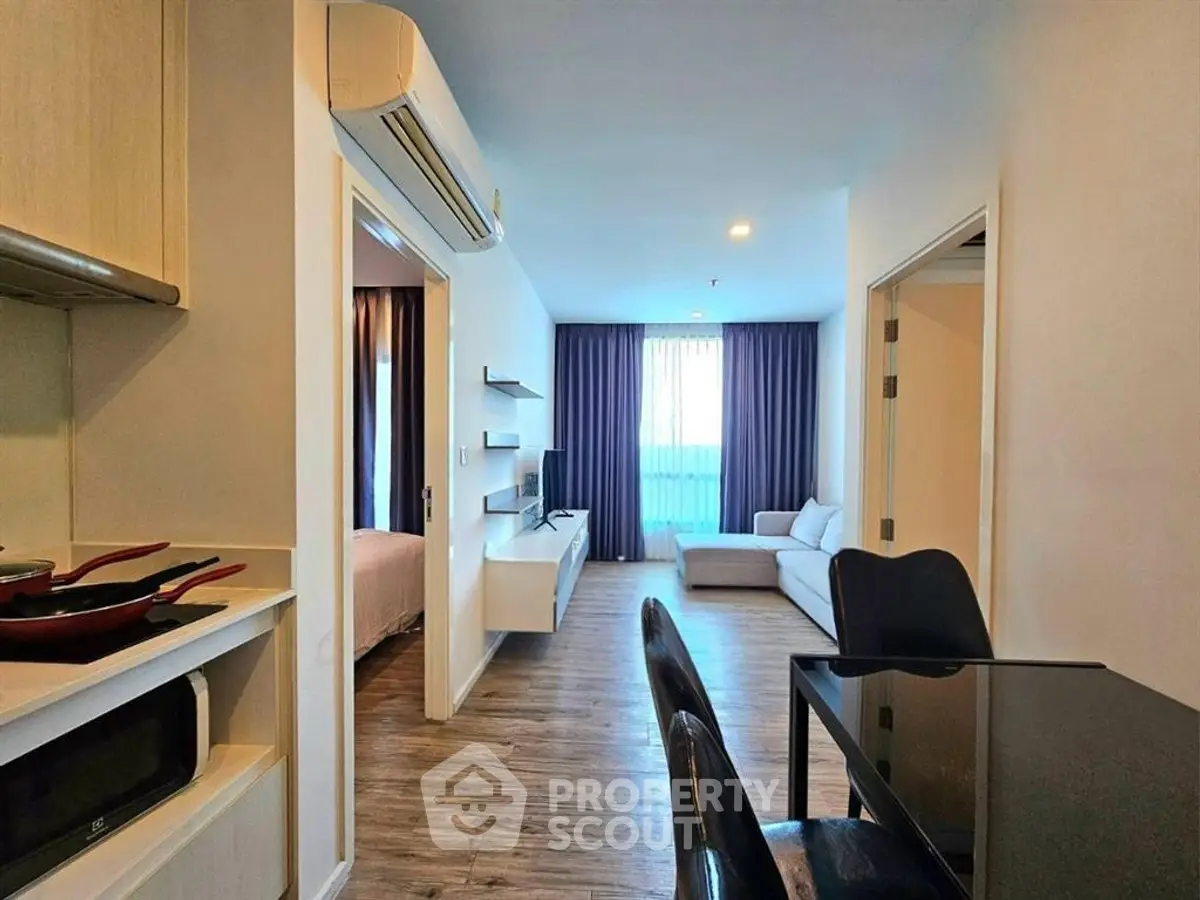 Modern apartment interior with open living room and dining area, featuring sleek furniture and natural light.