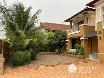 Charming two-story home with terracotta tiled driveway, lush landscaping, and a welcoming entrance, nestled in a serene neighborhood.