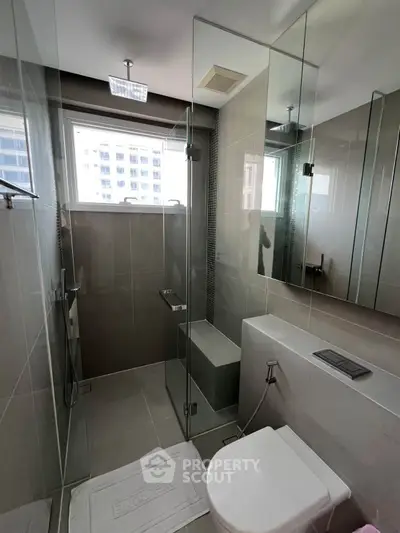 Modern bathroom with glass shower and sleek design in urban apartment.