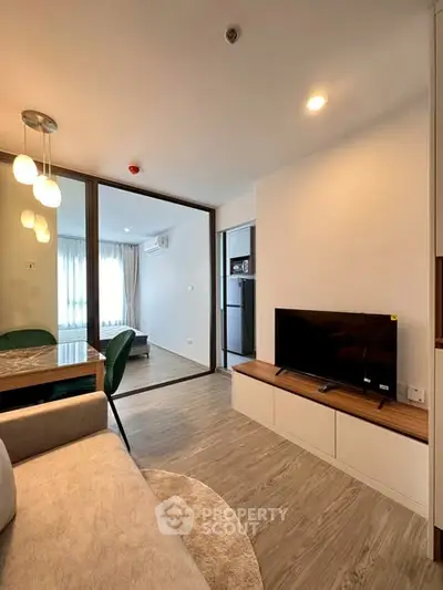 Modern living room with stylish decor and open layout, featuring a cozy seating area and a sleek TV setup.