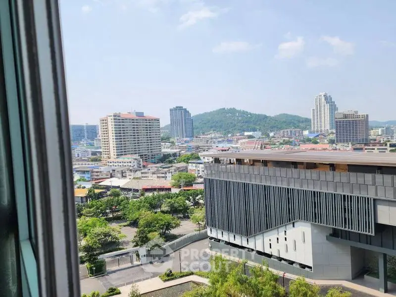 Stunning cityscape view from a high-rise building window, showcasing urban skyline and lush greenery.