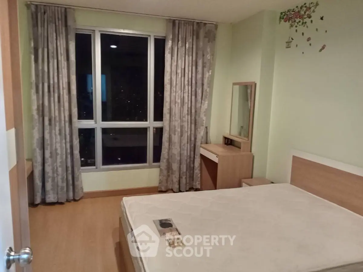 Cozy bedroom with large window and modern furnishings, perfect for city living.