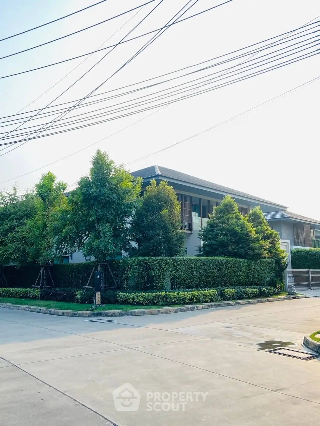 Modern two-story house with lush greenery and sleek design in a serene neighborhood.
