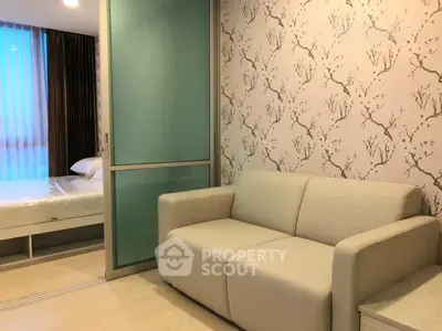 Modern apartment with stylish living room and cozy bedroom separated by sliding glass door.