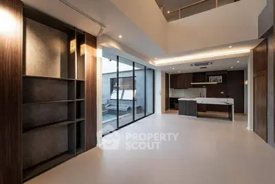 Spacious modern living room with open kitchen and large windows for natural light.