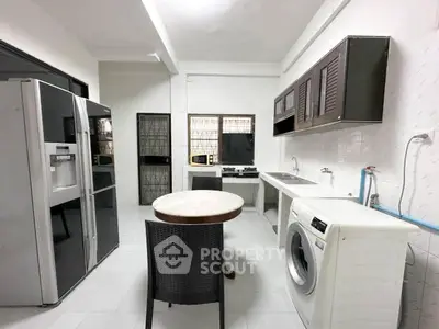 Spacious kitchen with modern appliances and washing machine in a bright, airy setting.