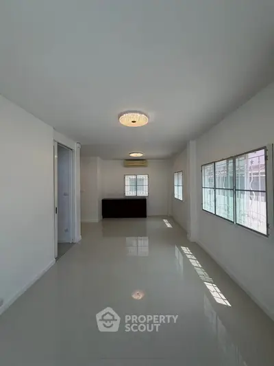 Spacious unfurnished room with large windows and glossy tiled floor, perfect for customization.