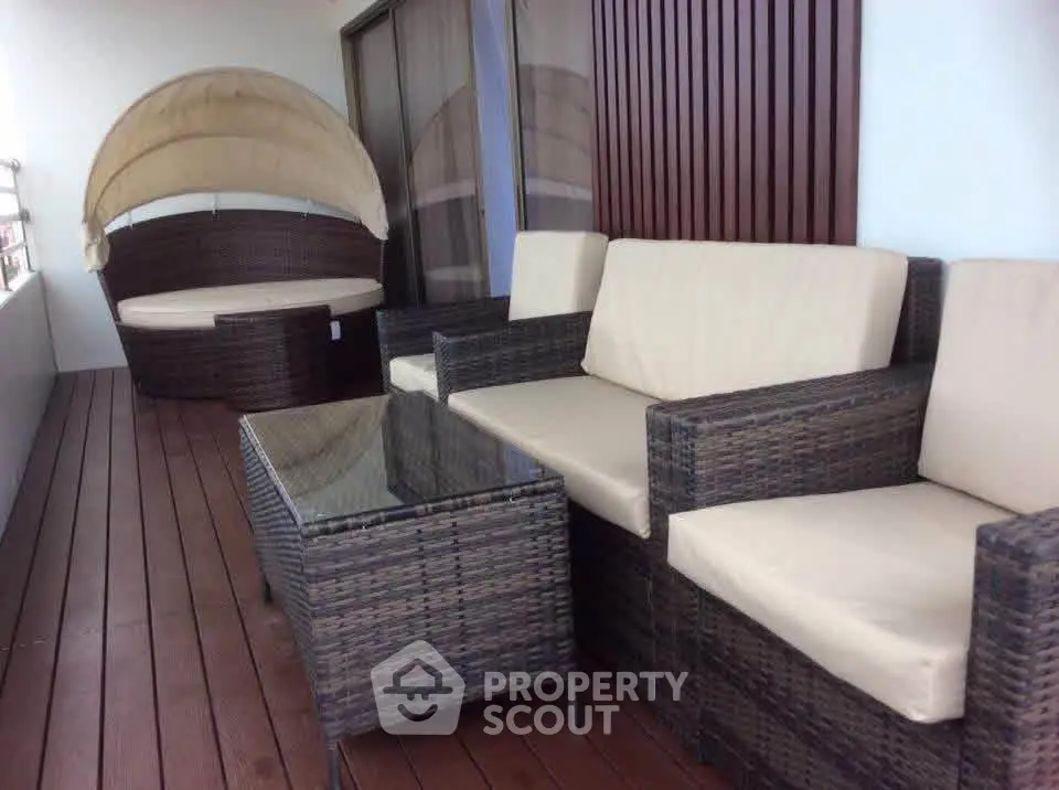 Spacious balcony with stylish outdoor furniture and wooden decking, perfect for relaxation.