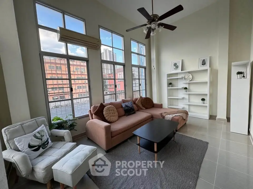 Spacious living room with large windows and modern decor in urban apartment.
