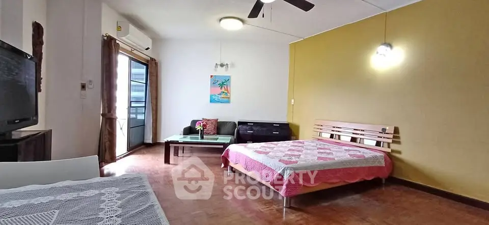 Spacious bedroom with cozy sitting area and balcony access.