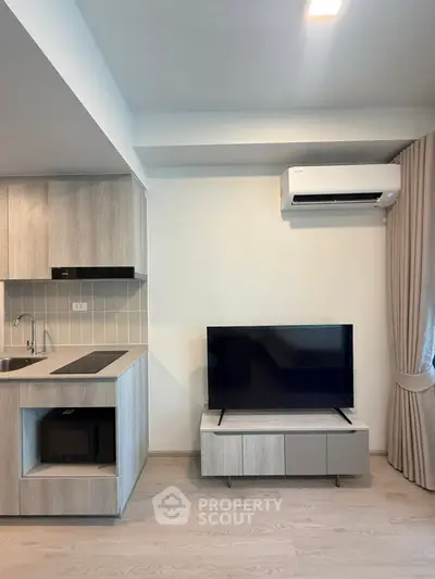 Modern living room with sleek kitchen and air conditioning, featuring a stylish TV setup.