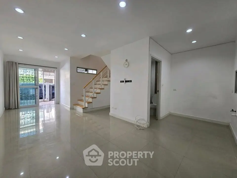 Spacious modern living room with staircase and large windows for natural light.