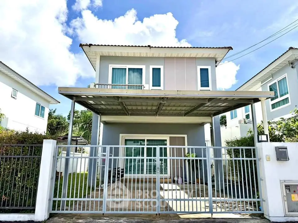 Charming two-story house with gated driveway and lush greenery, perfect for family living.