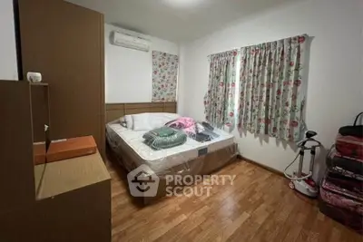 Cozy bedroom with floral curtains and wooden flooring, featuring a double bed and air conditioning.