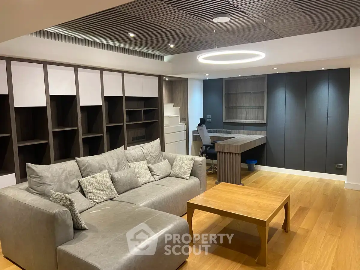 Modern living room with stylish furniture and wooden flooring, featuring a cozy sofa and sleek shelving.