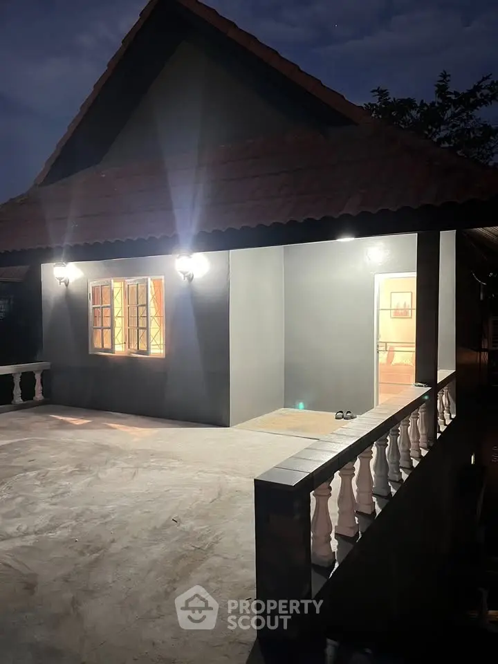 Charming single-story home with illuminated exterior and spacious patio at dusk.