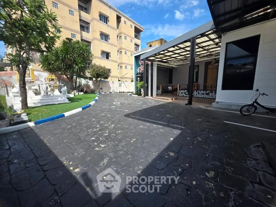 Spacious parking area with modern building and lush greenery, ideal for residential or commercial use.