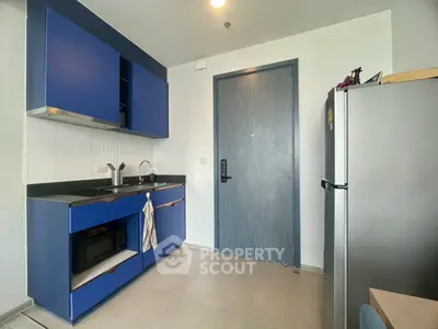 Modern kitchen with blue cabinets and sleek appliances in a stylish apartment.