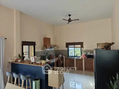 Modern kitchen with open layout, featuring sleek countertops, stylish bar stools, and natural light.