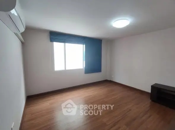 Spacious empty room with wooden flooring and large window